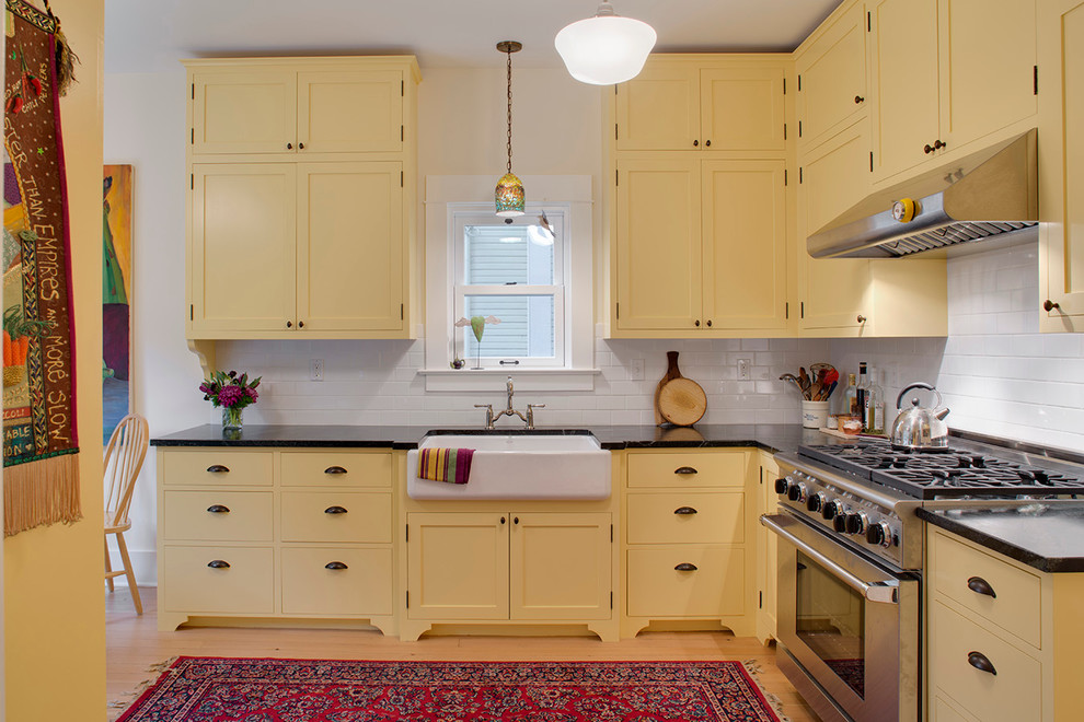 Klassische Küche mit Rückwand aus Metrofliesen, Landhausspüle, Schrankfronten im Shaker-Stil, gelben Schränken, Küchenrückwand in Weiß, Speckstein-Arbeitsplatte und Küchengeräten aus Edelstahl in Portland