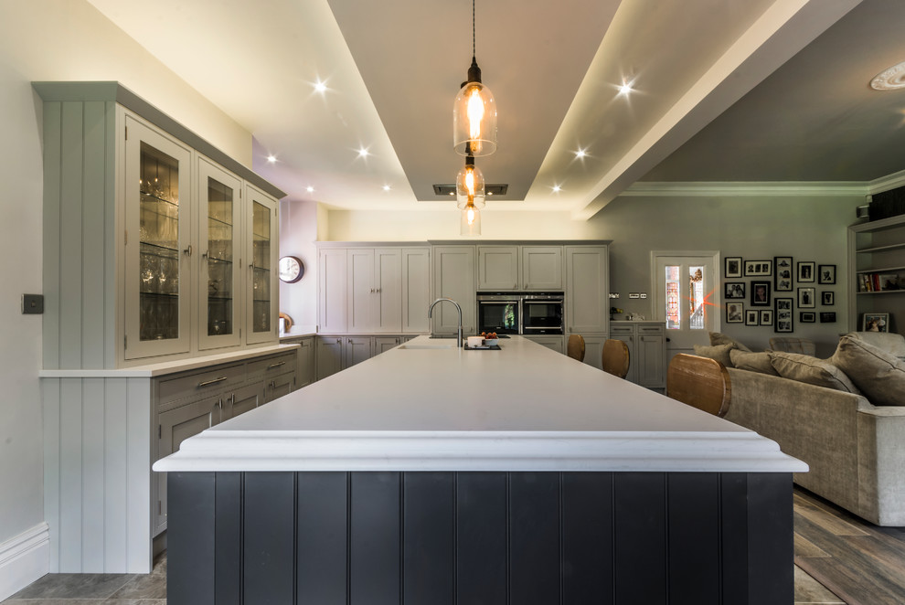 Modern inredning av ett mellanstort kök och matrum, med luckor med upphöjd panel, grå skåp, marmorbänkskiva och en köksö