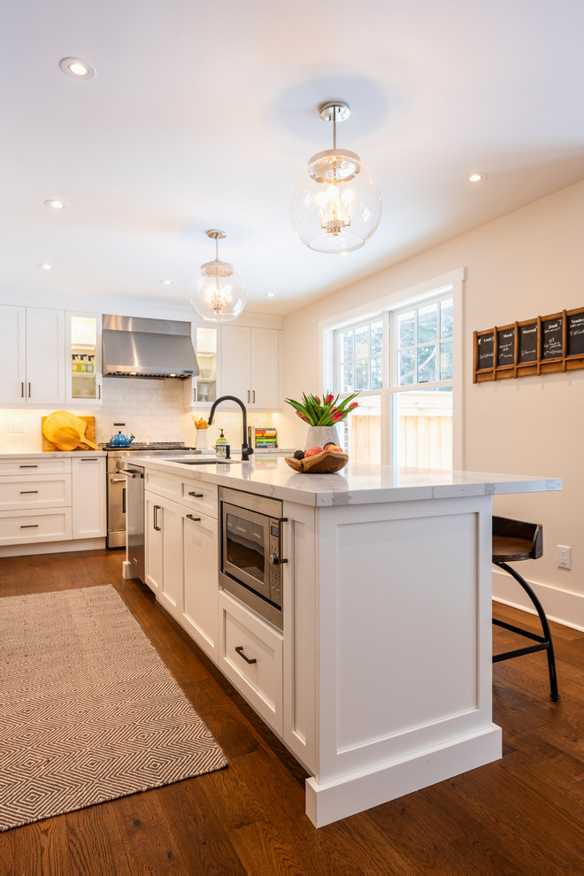 Immagine di una cucina moderna di medie dimensioni con lavello sottopiano, ante in stile shaker, ante bianche, paraspruzzi bianco, elettrodomestici in acciaio inossidabile, pavimento in legno massello medio, pavimento marrone e top bianco
