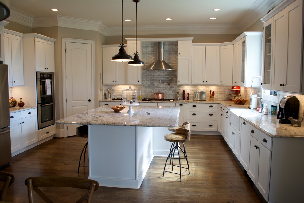 Eat-in kitchen - mid-sized traditional u-shaped medium tone wood floor eat-in kitchen idea in Raleigh with a farmhouse sink, shaker cabinets, white cabinets, granite countertops, gray backsplash, stone tile backsplash, stainless steel appliances and an island