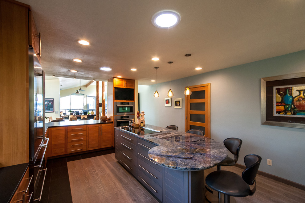 Mid-sized trendy u-shaped medium tone wood floor eat-in kitchen photo in Portland with an undermount sink, louvered cabinets, medium tone wood cabinets, granite countertops, multicolored backsplash, stone tile backsplash, stainless steel appliances and an island