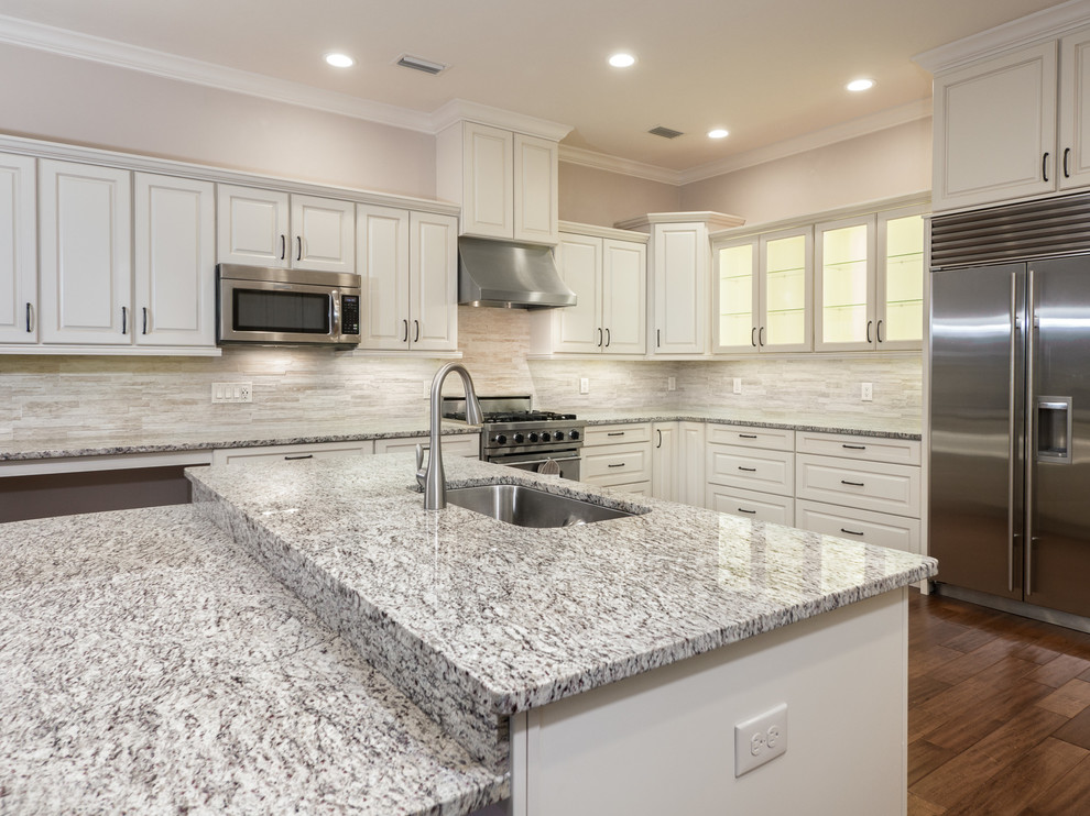 Inspiration for a large contemporary u-shaped medium tone wood floor eat-in kitchen remodel in Miami with a drop-in sink, beaded inset cabinets, white cabinets, gray backsplash, stainless steel appliances, an island, matchstick tile backsplash and granite countertops