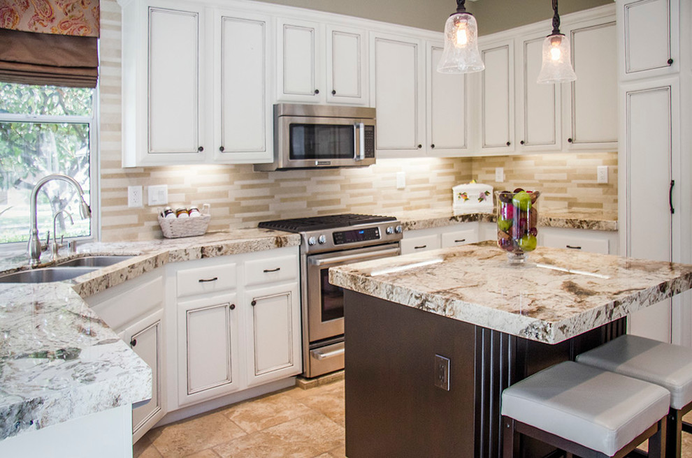 Mid-sized transitional u-shaped travertine floor open concept kitchen photo in Orange County with a double-bowl sink, recessed-panel cabinets, white cabinets, laminate countertops, multicolored backsplash, stone tile backsplash, stainless steel appliances and an island