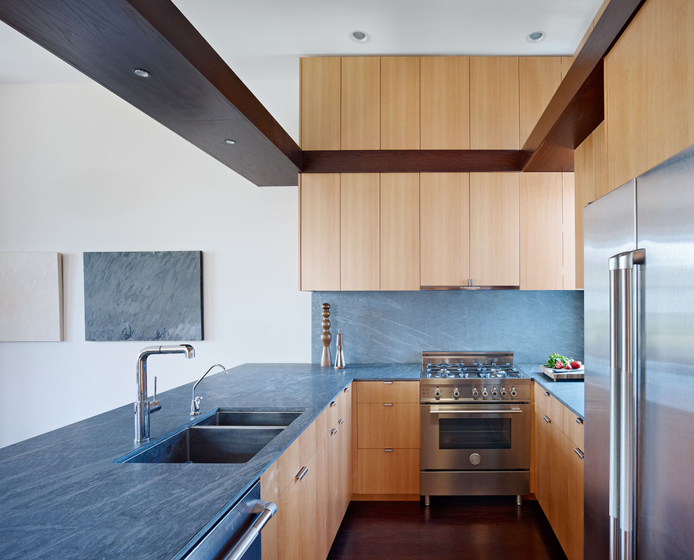 サンフランシスコにあるコンテンポラリースタイルのおしゃれなコの字型キッチン (ダブルシンク、フラットパネル扉のキャビネット、シルバーの調理設備、石スラブのキッチンパネル、淡色木目調キャビネット、青いキッチンカウンター) の写真