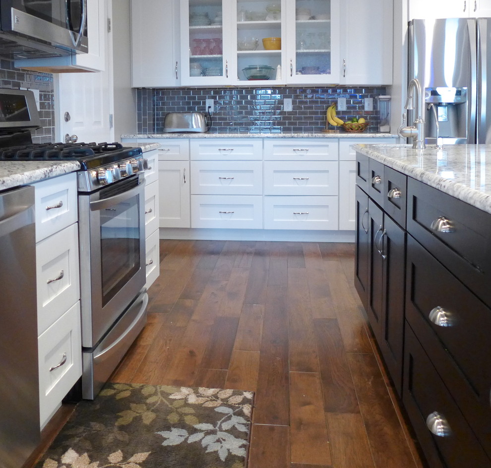 Idéer för att renovera ett stort vintage kök, med en undermonterad diskho, vita skåp, granitbänkskiva, grått stänkskydd, stänkskydd i tunnelbanekakel, rostfria vitvaror, skåp i shakerstil, mellanmörkt trägolv, en köksö och brunt golv