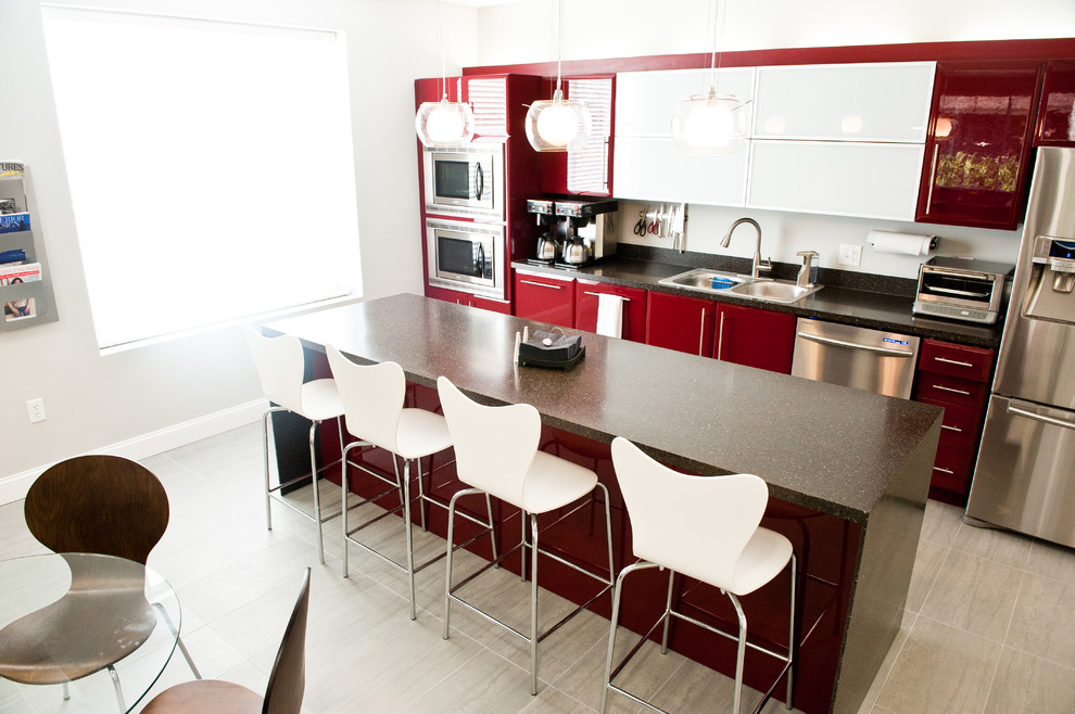 На фото: прямая, глянцевая кухня в современном стиле с обеденным столом, накладной мойкой, плоскими фасадами, красными фасадами и техникой из нержавеющей стали с