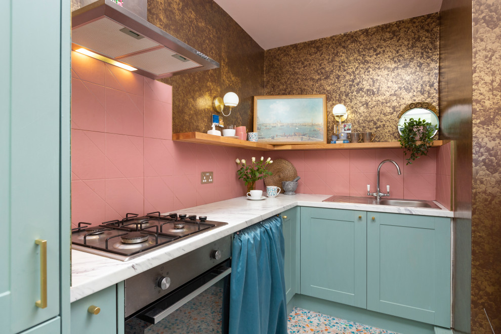 This is an example of a small eclectic l-shaped enclosed kitchen in Edinburgh with a single-bowl sink, shaker cabinets, blue cabinets, laminate countertops, pink splashback, ceramic splashback, stainless steel appliances, vinyl flooring, no island, multi-coloured floors and grey worktops.
