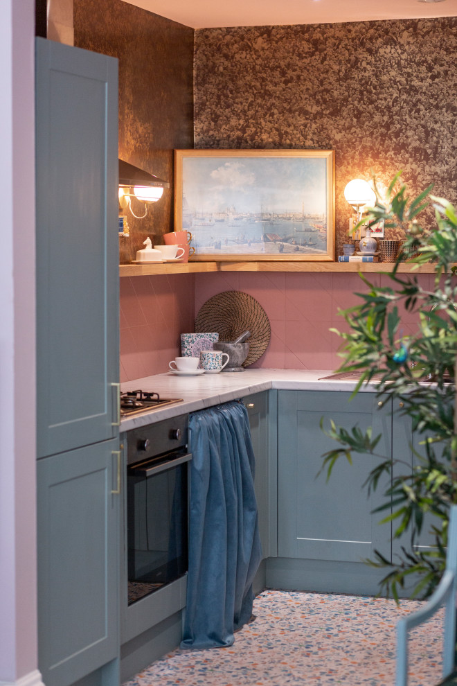Small eclectic l-shaped open plan kitchen in Edinburgh with a single-bowl sink, shaker cabinets, blue cabinets, laminate countertops, pink splashback, ceramic splashback, stainless steel appliances, vinyl flooring, no island, multi-coloured floors and grey worktops.