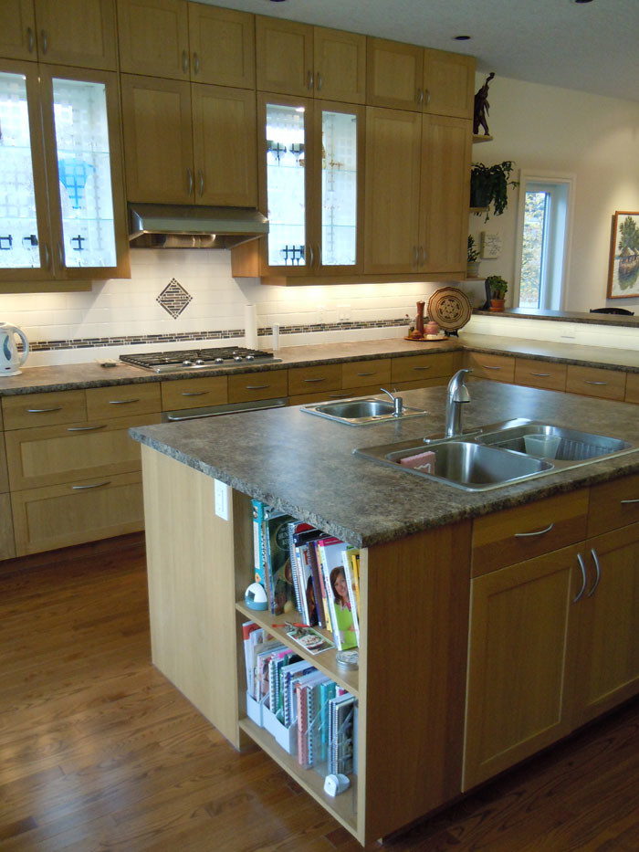 Inspiration for a craftsman l-shaped medium tone wood floor eat-in kitchen remodel in Calgary with a double-bowl sink, shaker cabinets, medium tone wood cabinets, laminate countertops, white backsplash, mosaic tile backsplash, stainless steel appliances and an island