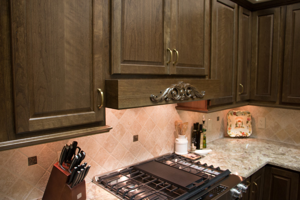 Klassisk inredning av ett mellanstort u-kök, med en undermonterad diskho, luckor med upphöjd panel, bruna skåp, bänkskiva i kvarts, beige stänkskydd, stänkskydd i stenkakel, rostfria vitvaror, klinkergolv i porslin och en köksö