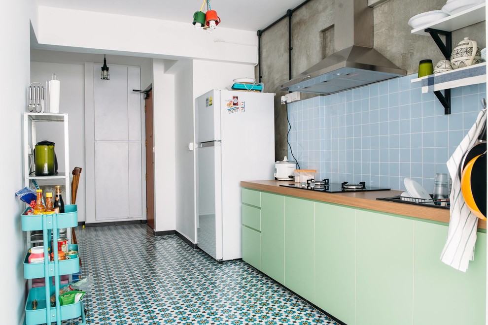 Inspiration for a medium sized rustic kitchen/diner in Singapore with a double-bowl sink, flat-panel cabinets, green cabinets, wood worktops, blue splashback, ceramic splashback, porcelain flooring and an island.