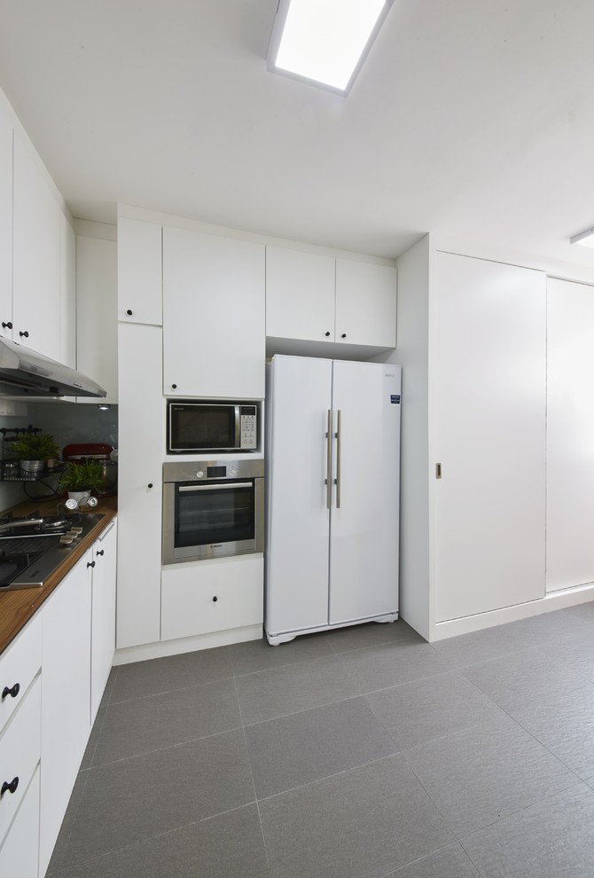 Cette photo montre une petite cuisine scandinave avec des portes de placard blanches et un sol en carrelage de céramique.