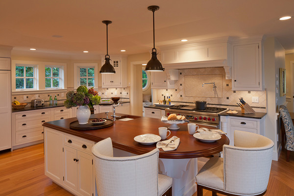 This is an example of a large nautical u-shaped kitchen/diner in Boston with a submerged sink, beaded cabinets, white cabinets, soapstone worktops, beige splashback, ceramic splashback, integrated appliances, light hardwood flooring, an island and brown floors.