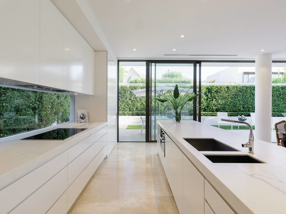 Inspiration pour une grande cuisine parallèle design avec un évier encastré, des portes de placard blanches, fenêtre, un sol en marbre, îlot et un sol beige.
