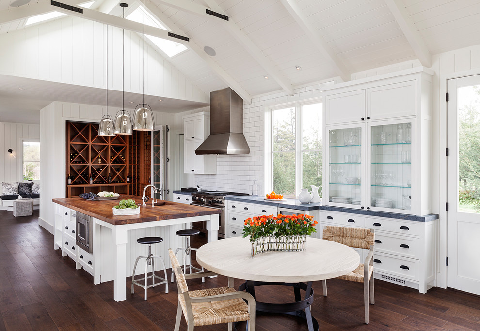 Inspiration for a mid-sized farmhouse u-shaped dark wood floor eat-in kitchen remodel in San Francisco with a drop-in sink, raised-panel cabinets, white cabinets, wood countertops, white backsplash, subway tile backsplash, stainless steel appliances and an island