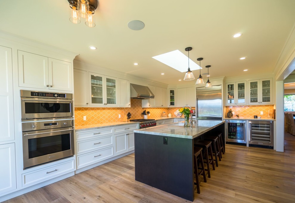 Inspiration for a large contemporary l-shaped light wood floor enclosed kitchen remodel in Orange County with an undermount sink, shaker cabinets, white cabinets, granite countertops, yellow backsplash, mosaic tile backsplash, stainless steel appliances and an island