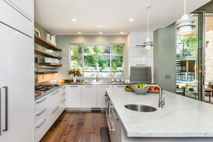 Photo of a large modern l-shaped kitchen/diner in San Francisco with a single-bowl sink, flat-panel cabinets, white cabinets, marble worktops, metallic splashback, stainless steel appliances, medium hardwood flooring and an island.