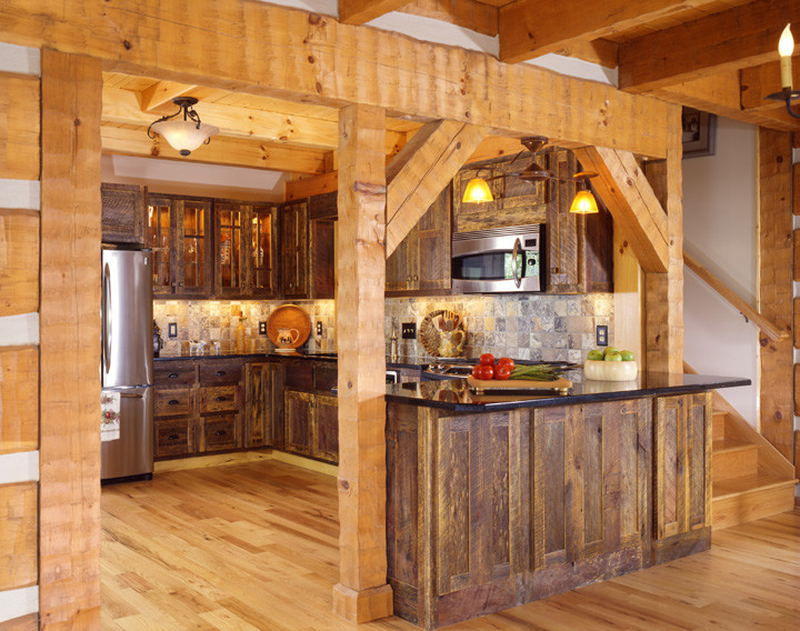 Large rustic u-shaped enclosed kitchen in Charlotte with a submerged sink, raised-panel cabinets, distressed cabinets, granite worktops, multi-coloured splashback, stone tiled splashback, stainless steel appliances, medium hardwood flooring and an island.