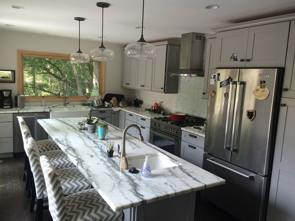 Idées déco pour une petite cuisine américaine parallèle moderne avec des portes de placard grises, plan de travail en marbre, une crédence grise, un électroménager en acier inoxydable, îlot et un sol marron.