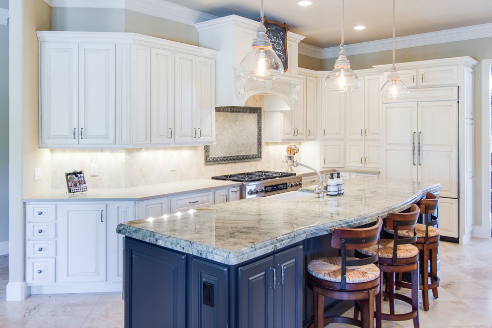 Example of a classic l-shaped eat-in kitchen design in Dallas with a farmhouse sink, raised-panel cabinets, white cabinets, granite countertops, beige backsplash, stone tile backsplash and stainless steel appliances