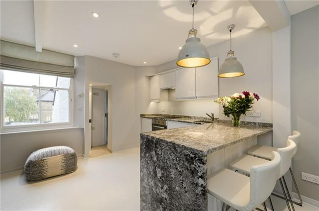 This is an example of a small modern l-shaped kitchen/diner in London with a submerged sink, flat-panel cabinets, white cabinets, granite worktops, painted wood flooring and an island.
