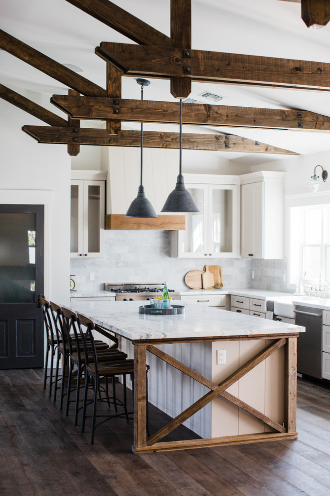 Example of a country l-shaped dark wood floor and brown floor kitchen design in Phoenix with a farmhouse sink, recessed-panel cabinets, white cabinets, gray backsplash, stainless steel appliances and an island