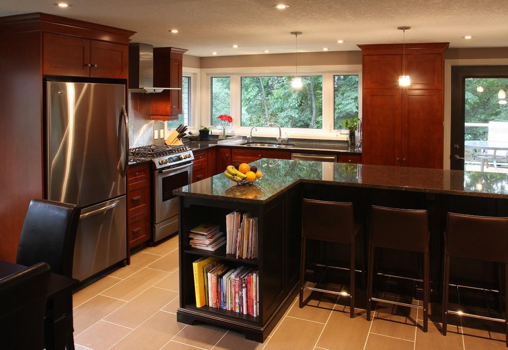 Modern inredning av ett l-kök, med rostfria vitvaror, en undermonterad diskho, luckor med infälld panel, skåp i mörkt trä och granitbänkskiva