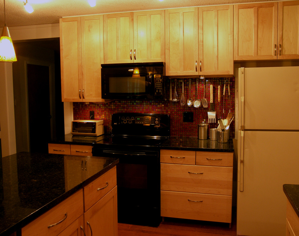 他の地域にある高級な小さなエクレクティックスタイルのおしゃれなキッチン (アンダーカウンターシンク、落し込みパネル扉のキャビネット、淡色木目調キャビネット、御影石カウンター、赤いキッチンパネル、ガラスタイルのキッチンパネル、黒い調理設備、ラミネートの床) の写真