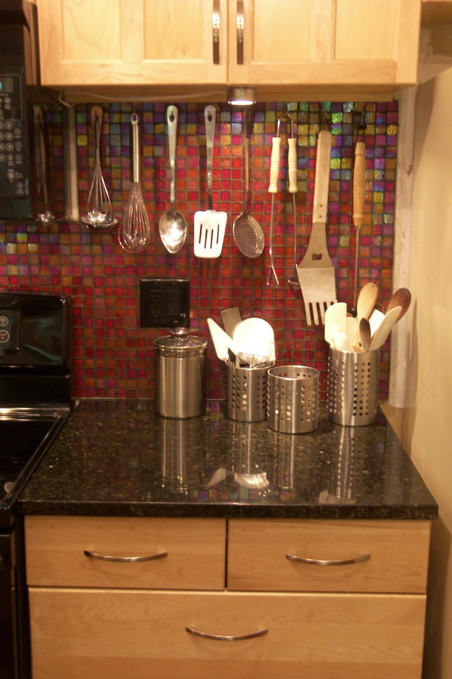 Exempel på ett litet eklektiskt kök, med en undermonterad diskho, luckor med infälld panel, skåp i ljust trä, granitbänkskiva, rött stänkskydd, stänkskydd i glaskakel, svarta vitvaror, laminatgolv och en köksö