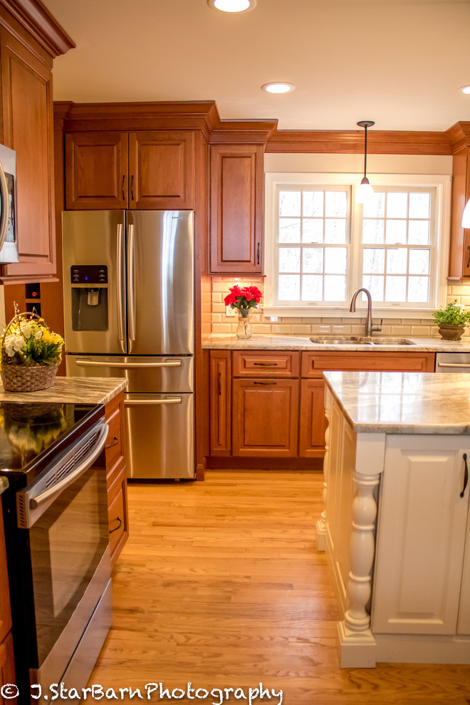 Bild på ett mellanstort vintage kök, med en dubbel diskho, luckor med upphöjd panel, skåp i mellenmörkt trä, marmorbänkskiva, vitt stänkskydd, stänkskydd i keramik, rostfria vitvaror, ljust trägolv och en köksö