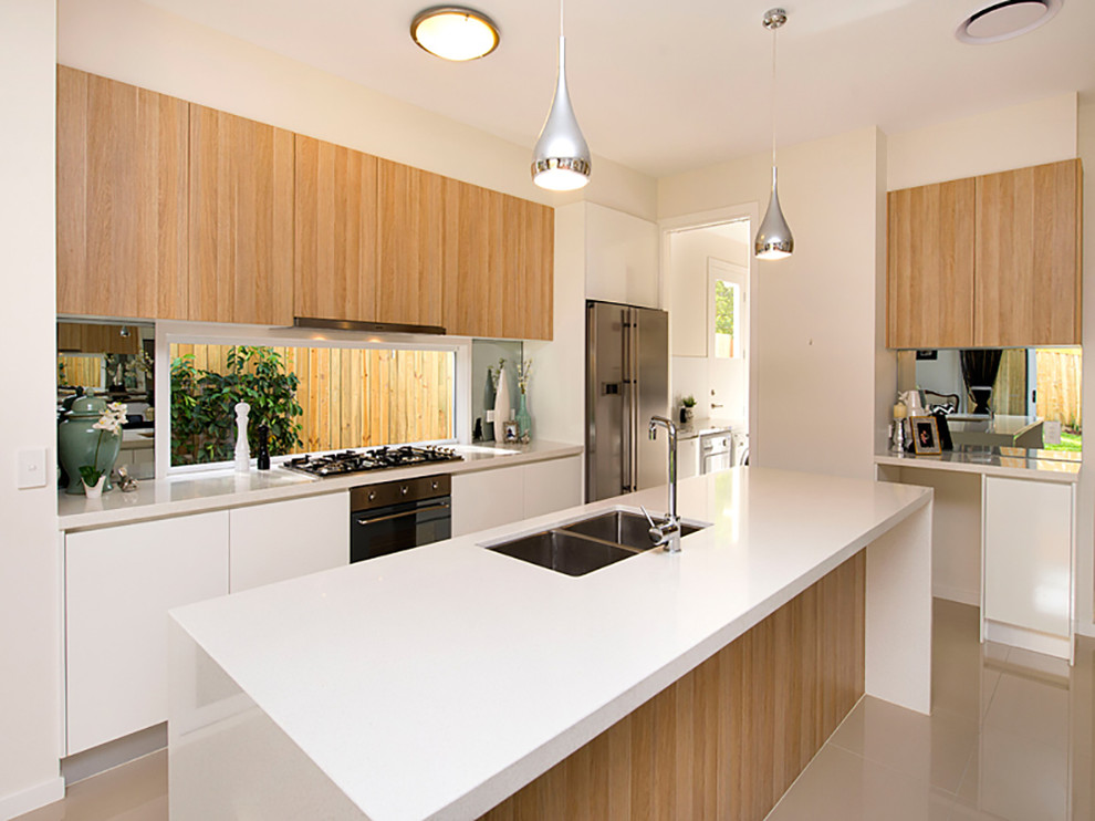Design ideas for a medium sized contemporary galley kitchen/diner in Brisbane with a submerged sink, light wood cabinets, quartz worktops, glass sheet splashback, stainless steel appliances, porcelain flooring and an island.