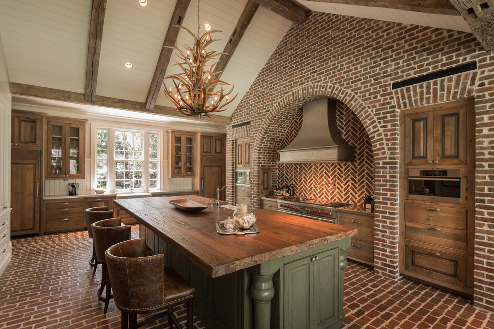 Inspiration for a rustic brick floor kitchen remodel in Houston with a farmhouse sink, medium tone wood cabinets, stainless steel countertops, stainless steel appliances and an island