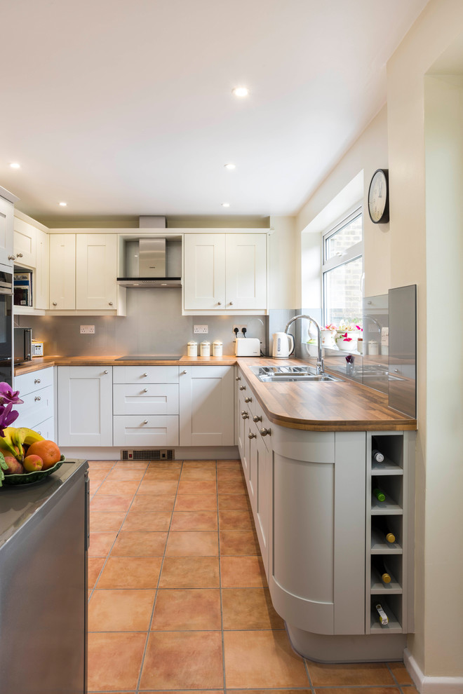 Kleine Klassische Küche in U-Form mit Schrankfronten im Shaker-Stil, grauen Schränken, Arbeitsplatte aus Holz, Küchenrückwand in Grau, Glasrückwand, Terrakottaboden und orangem Boden in Sussex