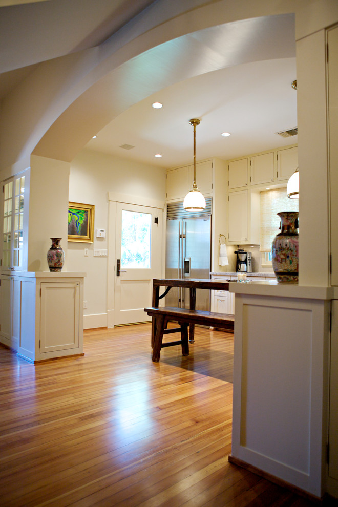 Exempel på ett mellanstort amerikanskt kök, med rostfria vitvaror, mellanmörkt trägolv, en köksö, luckor med infälld panel, vita skåp, granitbänkskiva, vitt stänkskydd, stänkskydd i tunnelbanekakel och en dubbel diskho