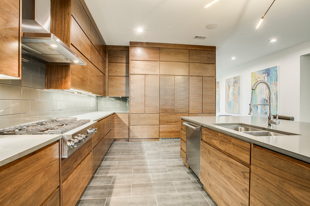 Inspiration for a large modern single-wall ceramic tile and gray floor eat-in kitchen remodel in Dallas with an undermount sink, flat-panel cabinets, medium tone wood cabinets, quartz countertops, gray backsplash, glass tile backsplash, stainless steel appliances and an island