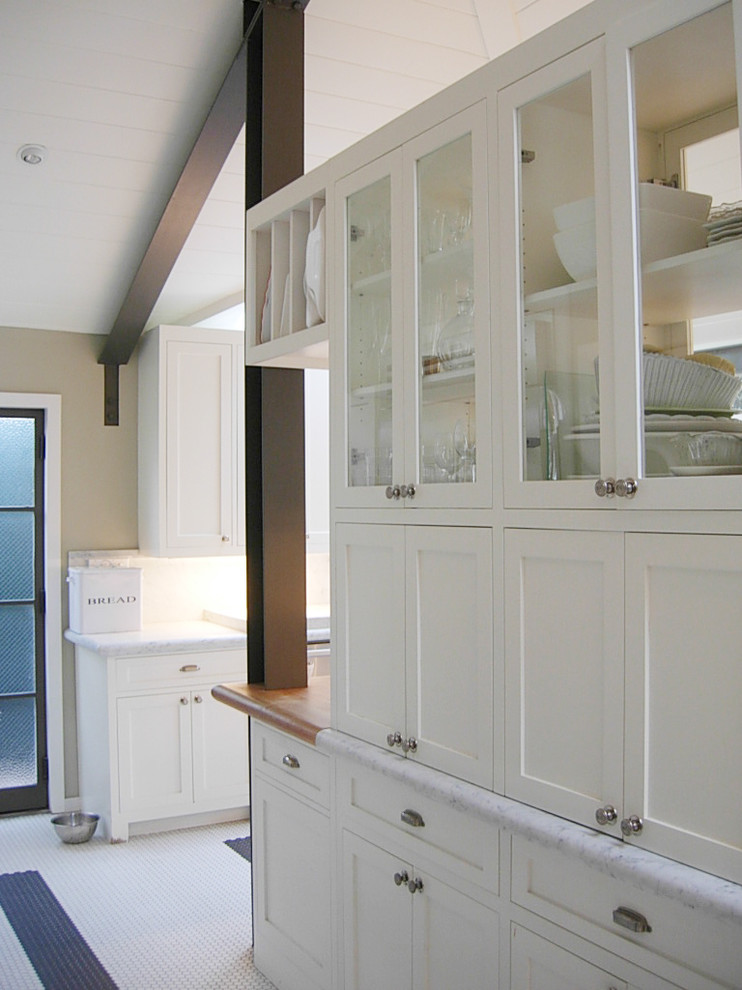 Ejemplo de cocina tradicional con armarios tipo vitrina, puertas de armario blancas y encimera de madera