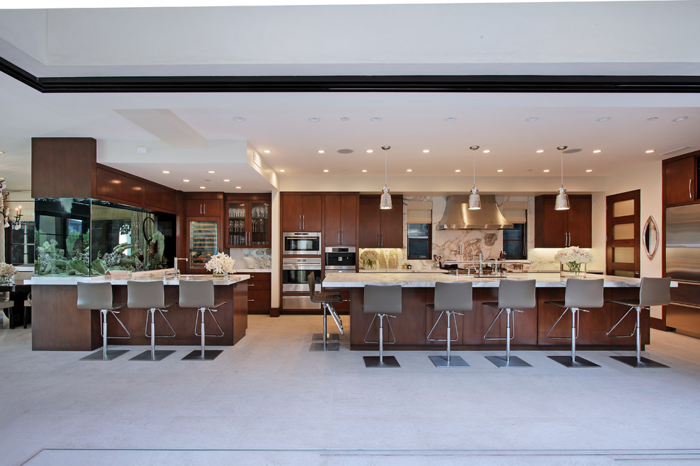 Geräumige Moderne Küche in U-Form mit flächenbündigen Schrankfronten, dunklen Holzschränken, Küchenrückwand in Weiß, Rückwand aus Stein, Küchengeräten aus Edelstahl und Kücheninsel in Orange County