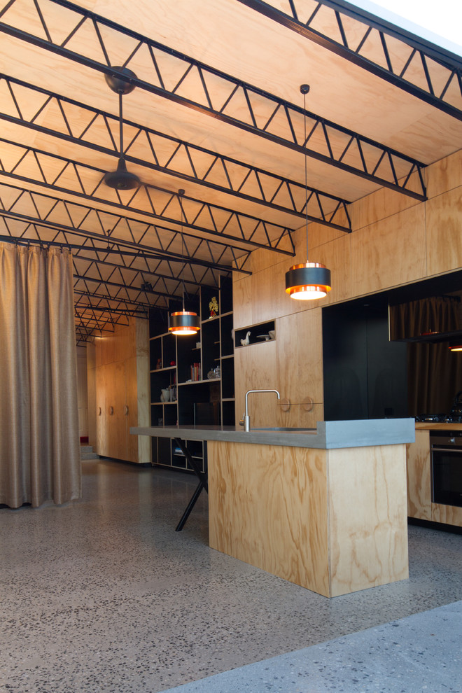 Свежая идея для дизайна: параллельная кухня-гостиная в стиле модернизм с накладной мойкой, светлыми деревянными фасадами, черным фартуком, черной техникой и островом - отличное фото интерьера