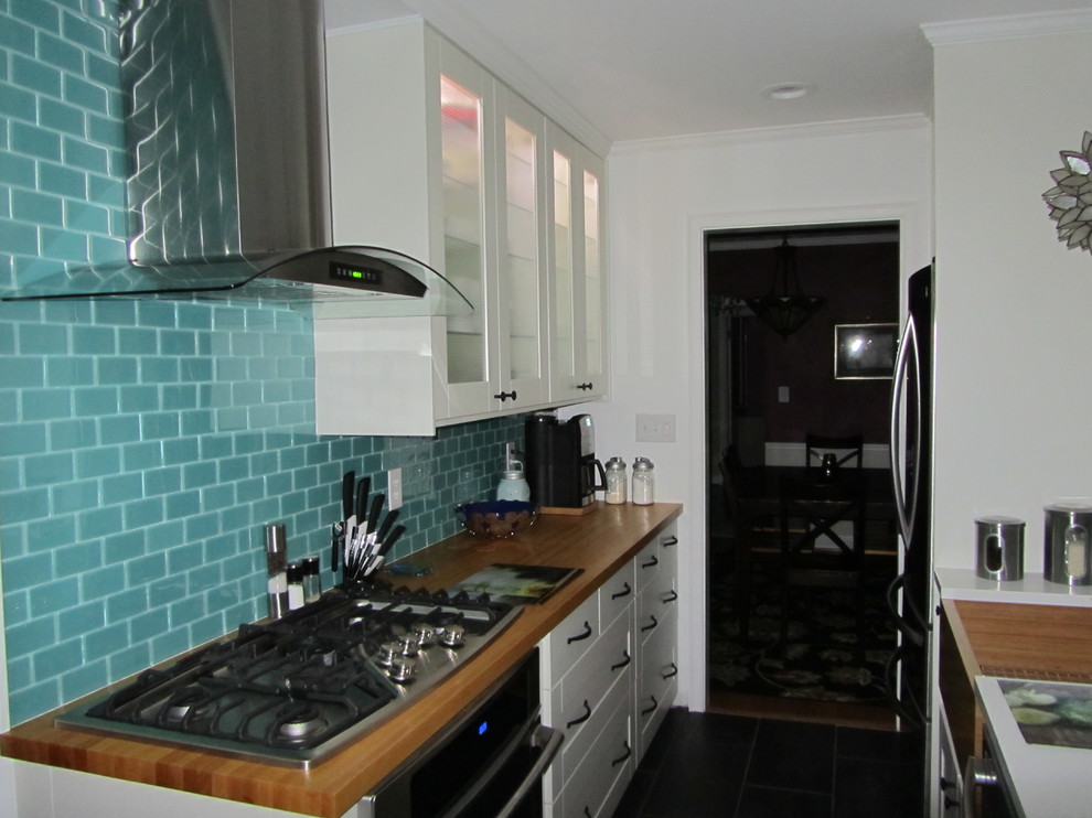Immagine di una piccola cucina parallela minimalista con ante di vetro, ante bianche, top in legno, paraspruzzi blu, paraspruzzi con piastrelle di vetro, elettrodomestici in acciaio inossidabile e pavimento in gres porcellanato