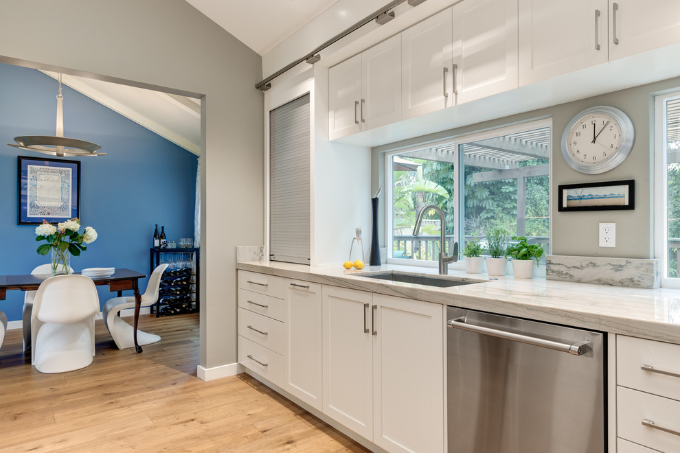 Example of a mid-sized transitional galley medium tone wood floor eat-in kitchen design in San Diego with an undermount sink, shaker cabinets, white cabinets, quartzite countertops, blue backsplash, porcelain backsplash, stainless steel appliances and no island
