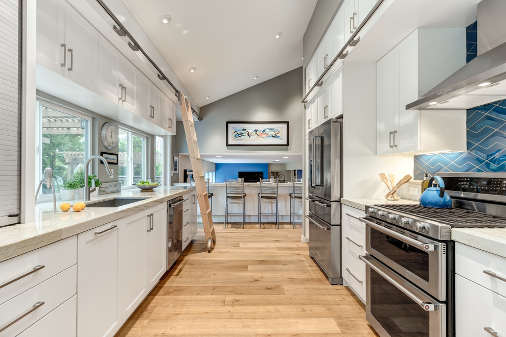 Inspiration for a mid-sized transitional galley medium tone wood floor eat-in kitchen remodel in San Diego with an undermount sink, shaker cabinets, white cabinets, quartzite countertops, blue backsplash, porcelain backsplash, stainless steel appliances and no island