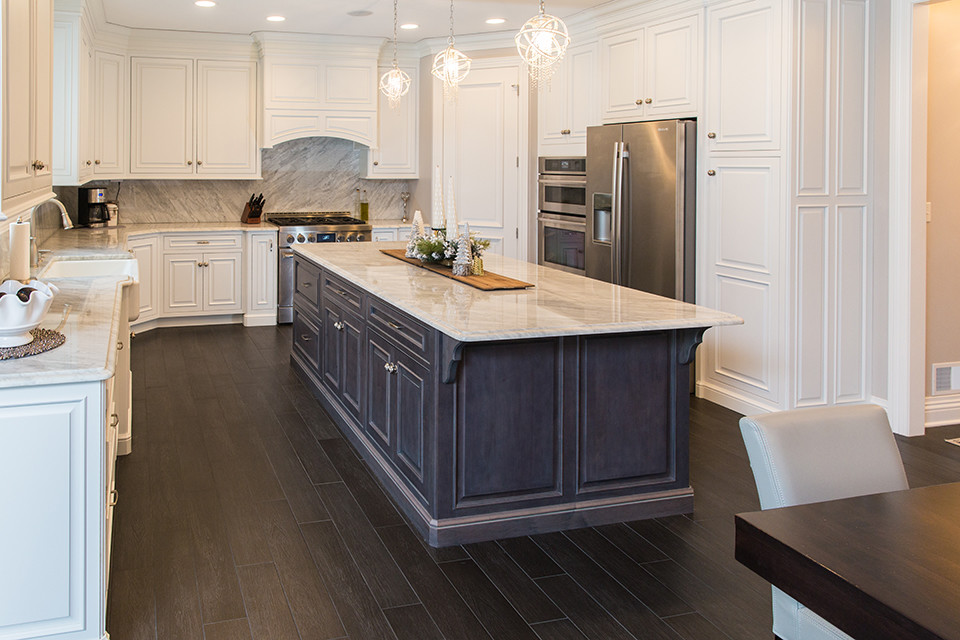 Example of a mid-sized arts and crafts u-shaped porcelain tile and brown floor eat-in kitchen design in Other with a farmhouse sink, shaker cabinets, white cabinets, marble countertops, gray backsplash, stone tile backsplash, stainless steel appliances and an island
