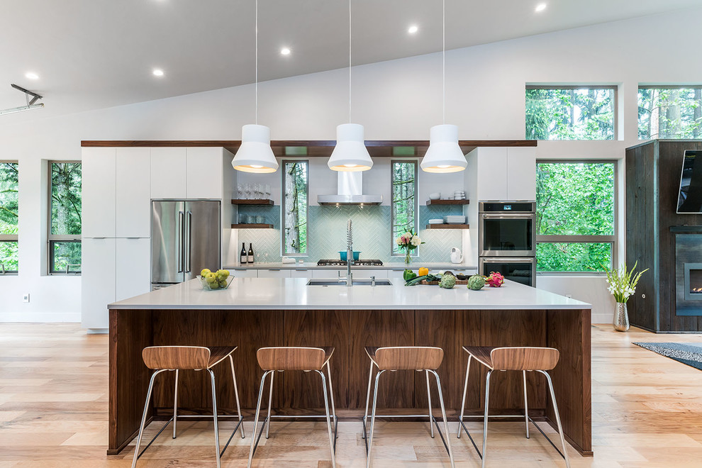 Imagen de cocina comedor contemporánea grande con fregadero bajoencimera, armarios con paneles lisos, puertas de armario blancas, electrodomésticos de acero inoxidable, suelo de madera clara, una isla, suelo beige, encimera de cuarzo compacto, salpicadero azul, salpicadero de azulejos de vidrio y encimeras grises