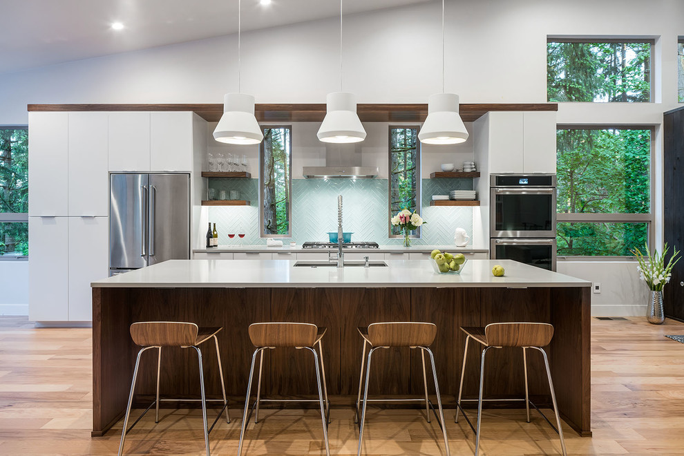 Open concept kitchen - huge modern galley light wood floor and beige floor open concept kitchen idea in Other with an undermount sink, flat-panel cabinets, quartz countertops, blue backsplash, glass tile backsplash, stainless steel appliances and an island