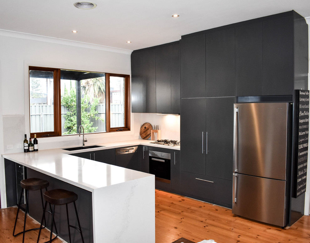 Inspiration for a medium sized contemporary u-shaped open plan kitchen in Adelaide with a double-bowl sink, blue cabinets, white splashback, stone slab splashback, stainless steel appliances, flat-panel cabinets, marble worktops, medium hardwood flooring and a breakfast bar.