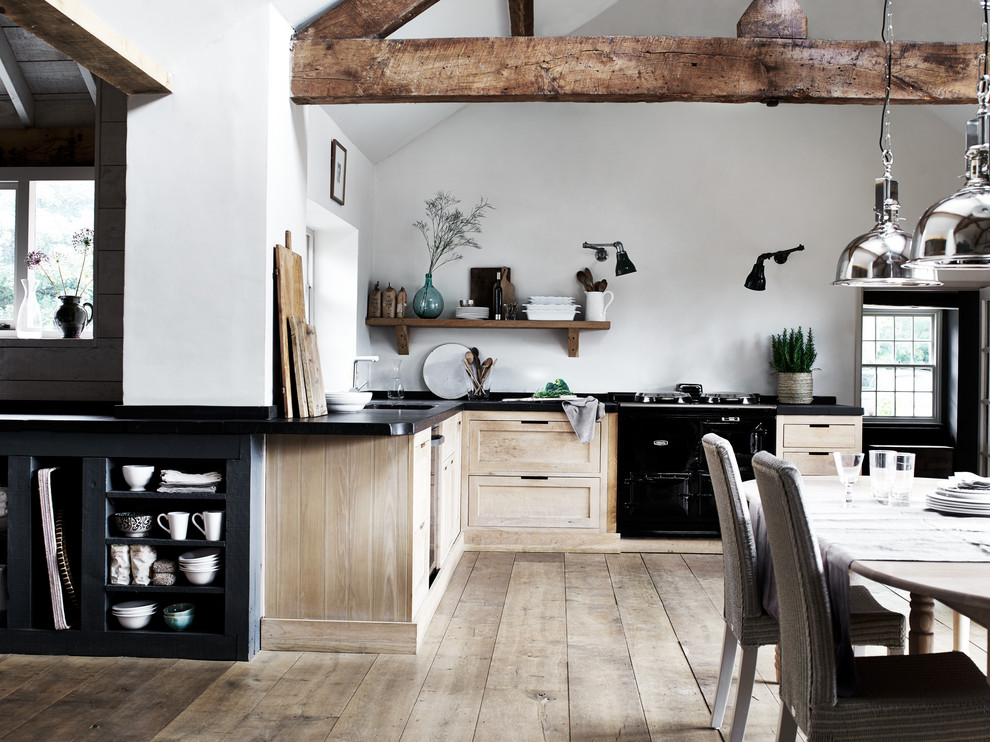 Nordische Küche in L-Form mit Unterbauwaschbecken, Schrankfronten im Shaker-Stil, hellen Holzschränken, schwarzen Elektrogeräten, braunem Holzboden, braunem Boden und schwarzer Arbeitsplatte in Belfast