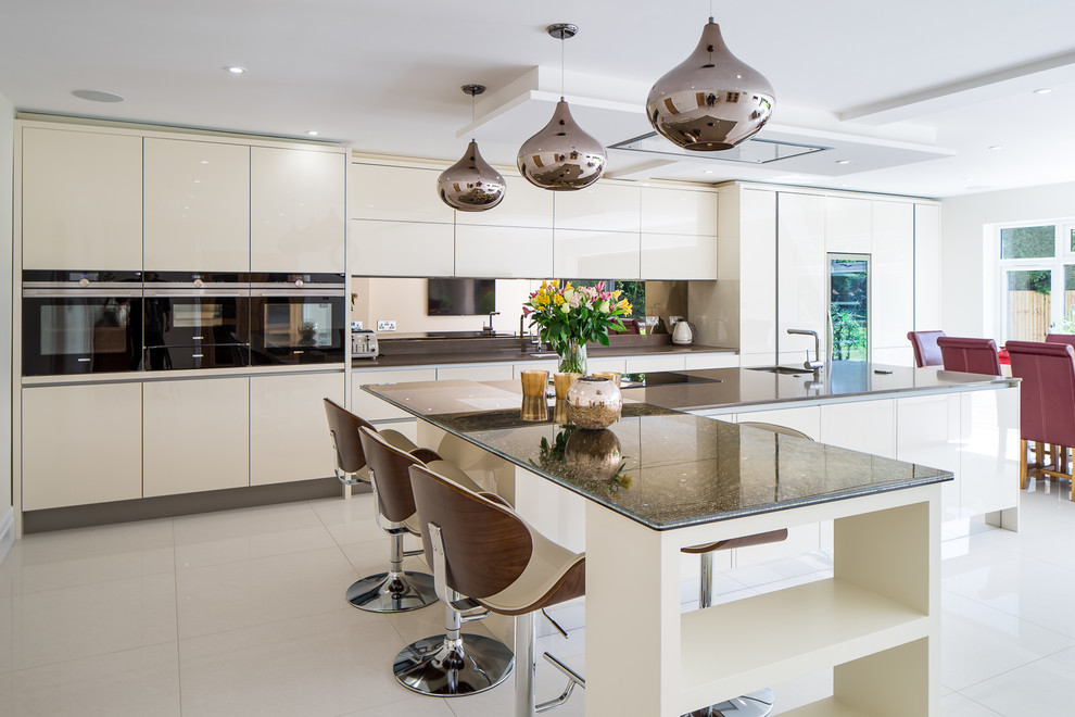Example of a trendy white floor eat-in kitchen design in Other with an undermount sink, flat-panel cabinets, beige cabinets, mirror backsplash, black appliances, two islands and black countertops