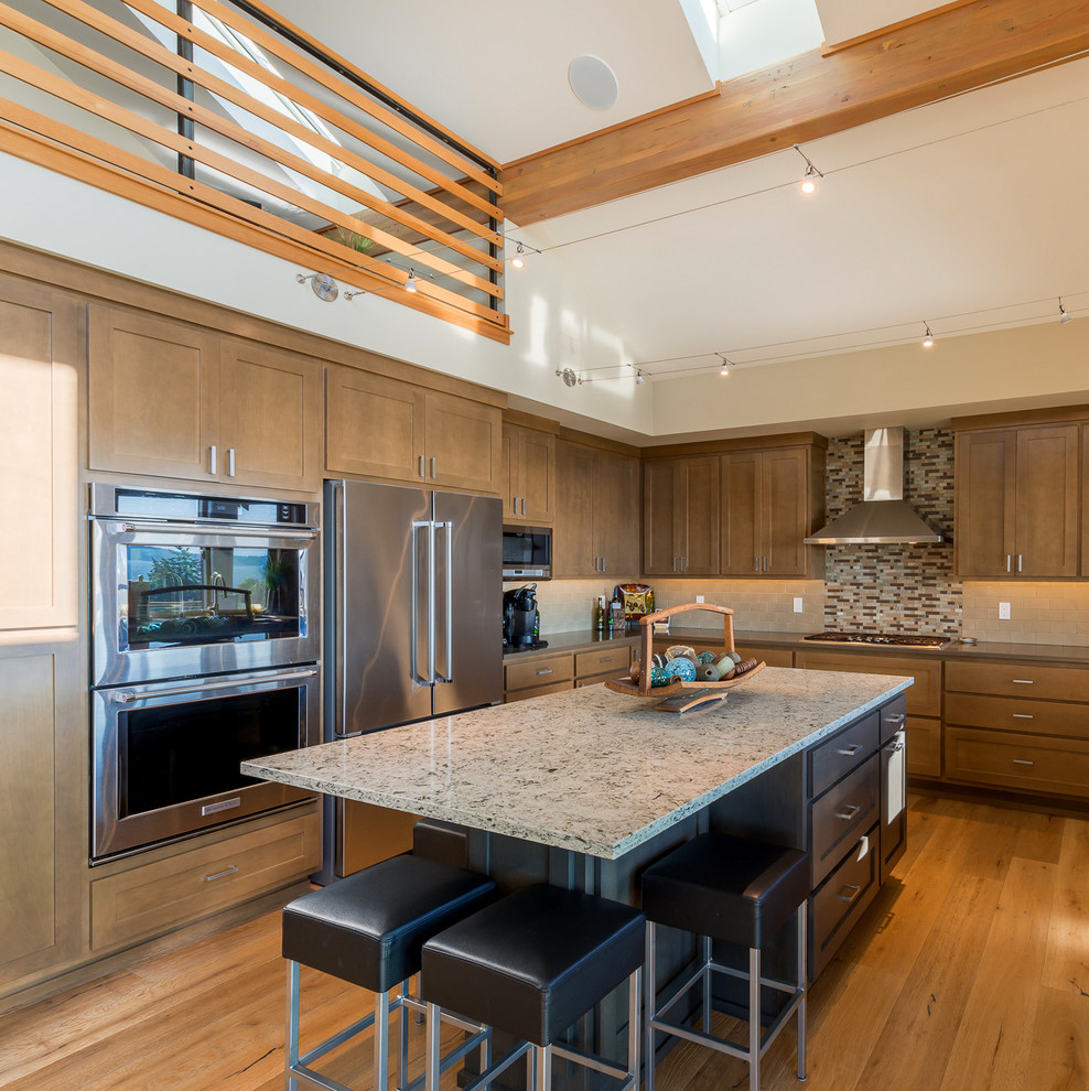 Cette photo montre une cuisine tendance en L et bois foncé avec un placard à porte shaker, une crédence multicolore, un électroménager en acier inoxydable, un sol en bois brun, îlot et un sol marron.