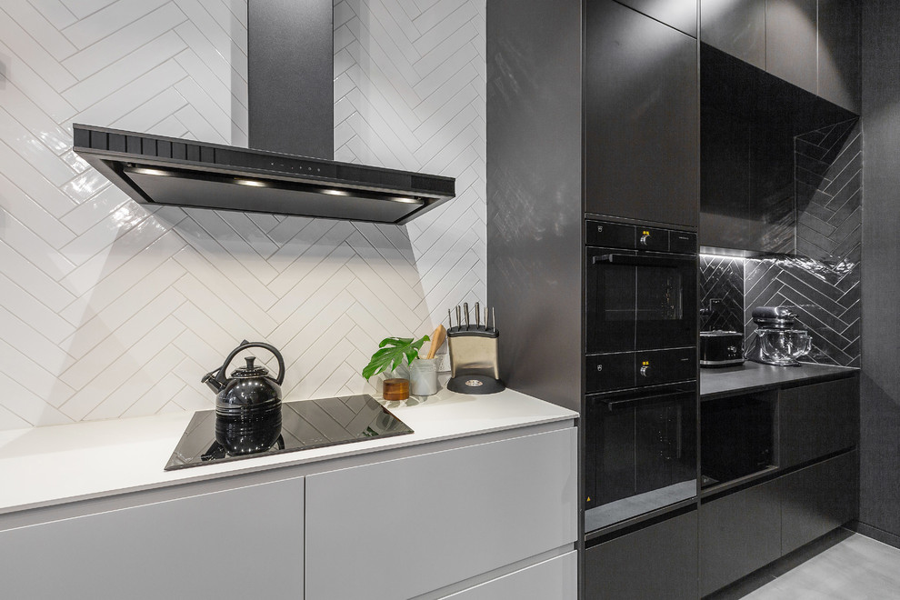 Foto på ett mellanstort funkis kök, med en undermonterad diskho, släta luckor, svarta skåp, marmorbänkskiva, stänkskydd i mosaik, svarta vitvaror, betonggolv och grått golv