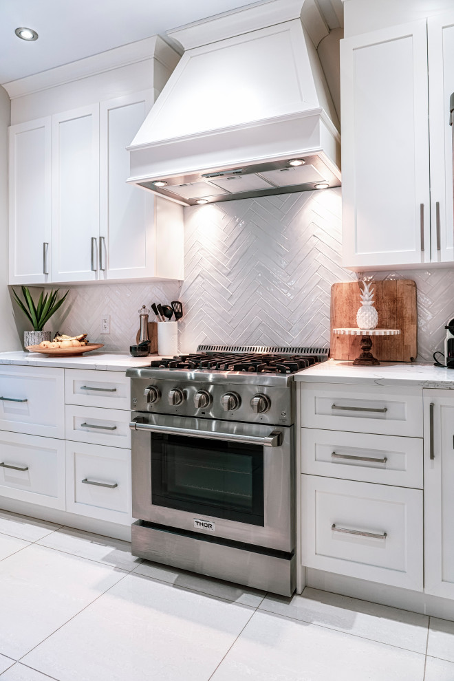Example of a mid-sized cottage u-shaped ceramic tile and beige floor kitchen design in Montreal with an undermount sink, shaker cabinets, white cabinets, quartz countertops, white backsplash, subway tile backsplash, stainless steel appliances, an island and white countertops
